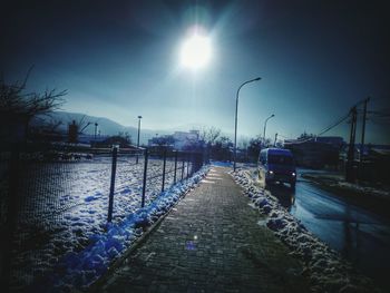 Illuminated street lights by trees against sky