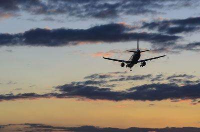 Low angle view of airplane flying against sky during sunset