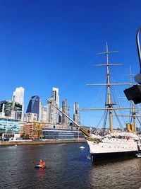 Sailboats in river against blue sky