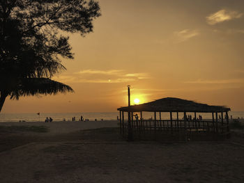 Silhouette people on beach against sky during sunset