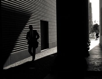 Silhouette of woman walking on building