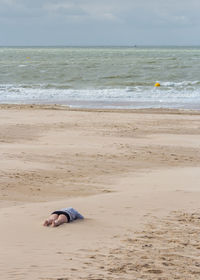 Low section of woman lying down on sand at beach