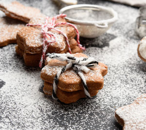 Star shaped baked gingerbread cookies sprinkled with powdered sugar on a black table, close up