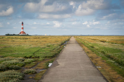 Road amidst field against sky