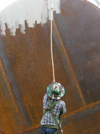 Rear view of man painting rusty metallic wall