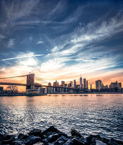 River by buildings against sky during sunset