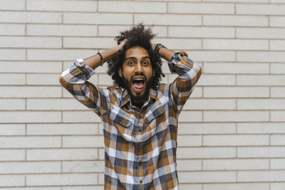 Portrait of young man standing against wall