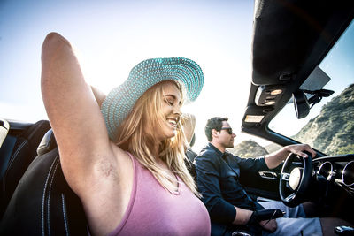 Portrait of smiling young woman sitting on car