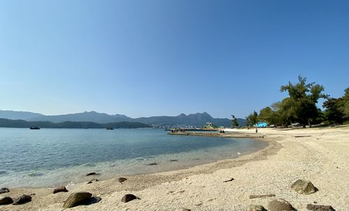 Scenic view of beach against clear blue sky