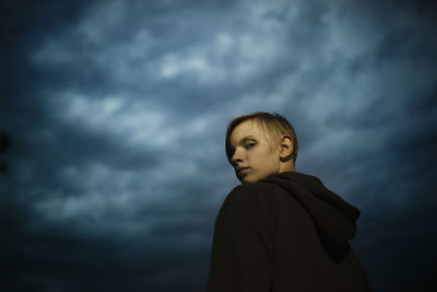 Side view of young man standing against sky