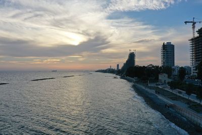 Scenic view of sea and buildings against sky during sunset