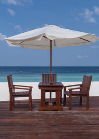 Chairs and table on beach against sky