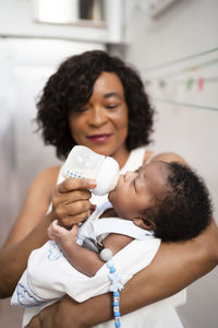 Mature woman feeding baby boy at home