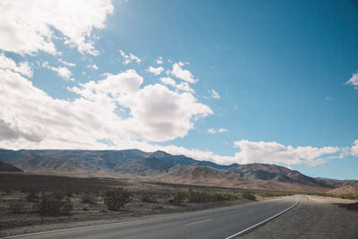 Scenic view of road by mountains against sky