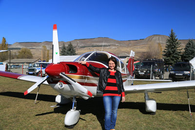 Air show. a young woman stands next to a small plane and smiles