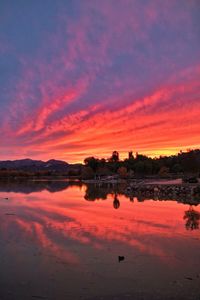 Scenic view of lake against dramatic sky during sunset