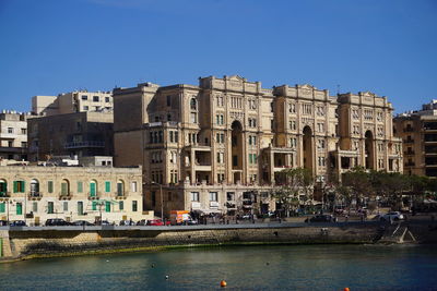 Buildings in city against clear blue sky