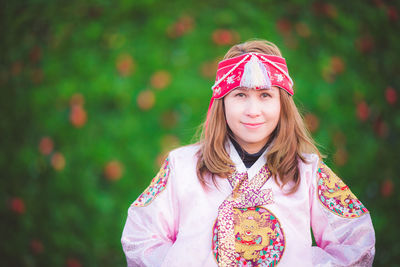 Portrait of a beautiful young woman standing against pink background