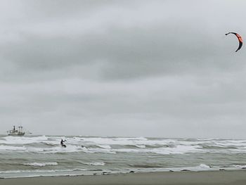 Man flying over beach against sky