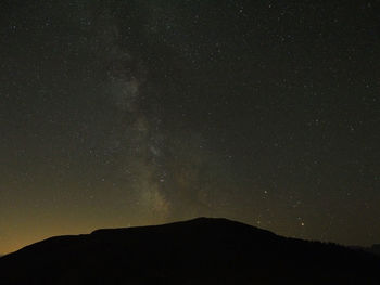 Scenic view of star field above silhouette mountains at night