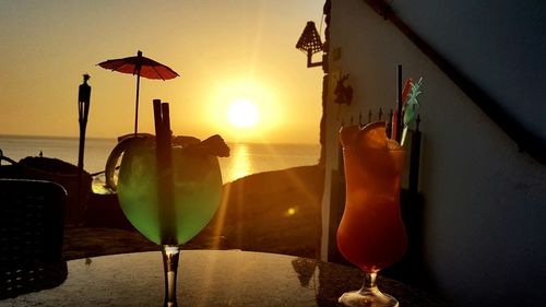 Close-up of beer on table against sea during sunset