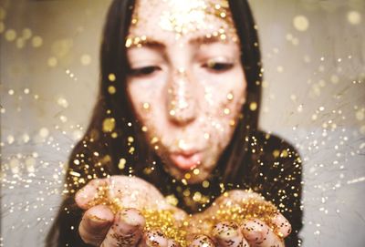 Close-up of young woman blowing confetti