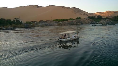 Boat sailing on river against mountain