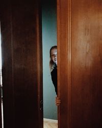 Portrait of smiling young woman standing against door at home