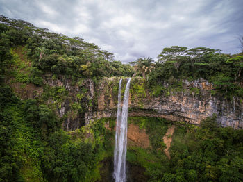 Scenic view of waterfall in forest against sky