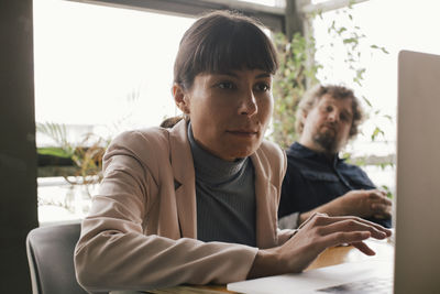 Businesswoman using laptop while working at desk in office