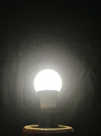 Illuminated light bulb against black background