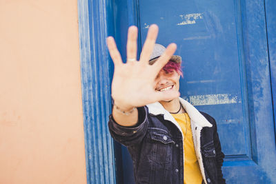 Portrait of smiling woman standing against wall