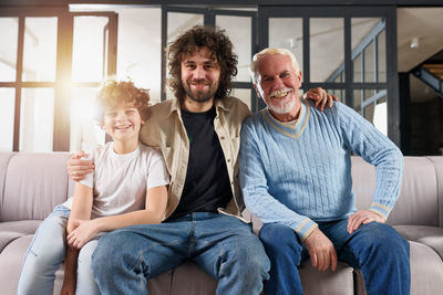 Portrait of smiling family members sitting on sofa at home