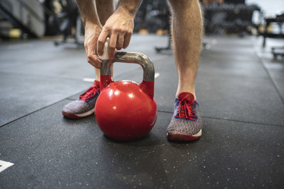 Legs of man holding kettlebell while standing in gym