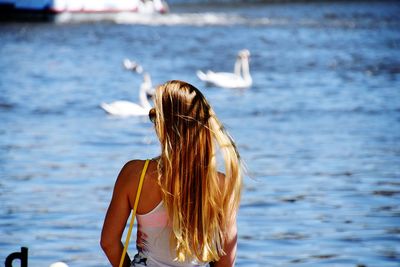 Rear view of woman standing by lake