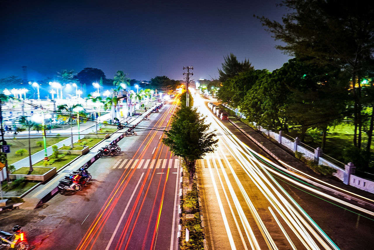 transportation, illuminated, road, motion, speed, night, long exposure, light trail, street, tree, mode of transportation, city, high angle view, traffic, land vehicle, street light, plant, blurred motion, highway, car, no people, outdoors, multiple lane highway