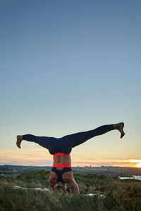 Rear view of man with arms raised standing against clear sky