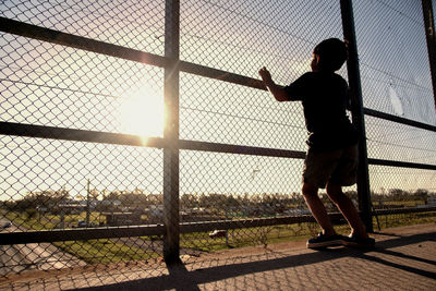 Portrait of kid looking through wired fence