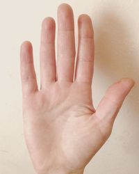 Close-up of hand showing stop gesture against white wall