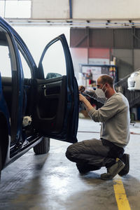 Auto mechanic working on car door in repair shop