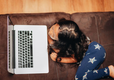 Cute girl using laptop while lying on sofa at home
