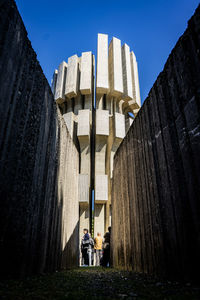 Low angle view of people standing amidst buildings against clear sky