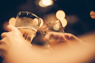 Cropped hands of people toasting beer glasses in bar