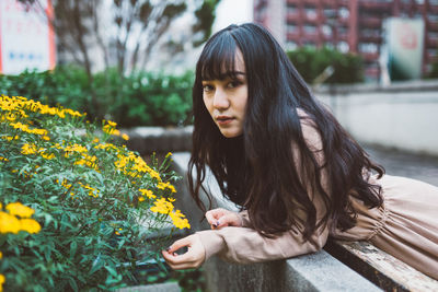 Portrait of beautiful young woman with yellow flower