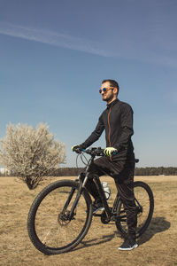 Young man standing with one foot on the bike pedal