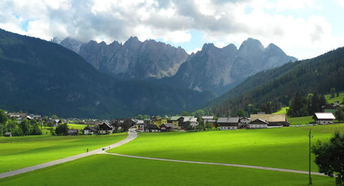 Scenic view of field and houses against sky