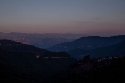 Scenic view of silhouette mountains against romantic sky at sunset