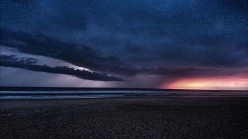 Scenic view of sea against dramatic sky during sunset