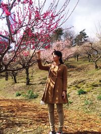 Full length of young woman standing against tree