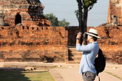 Young man walk on a wooden bridge in the morning at temple in old city of ayutthaya in thailand.